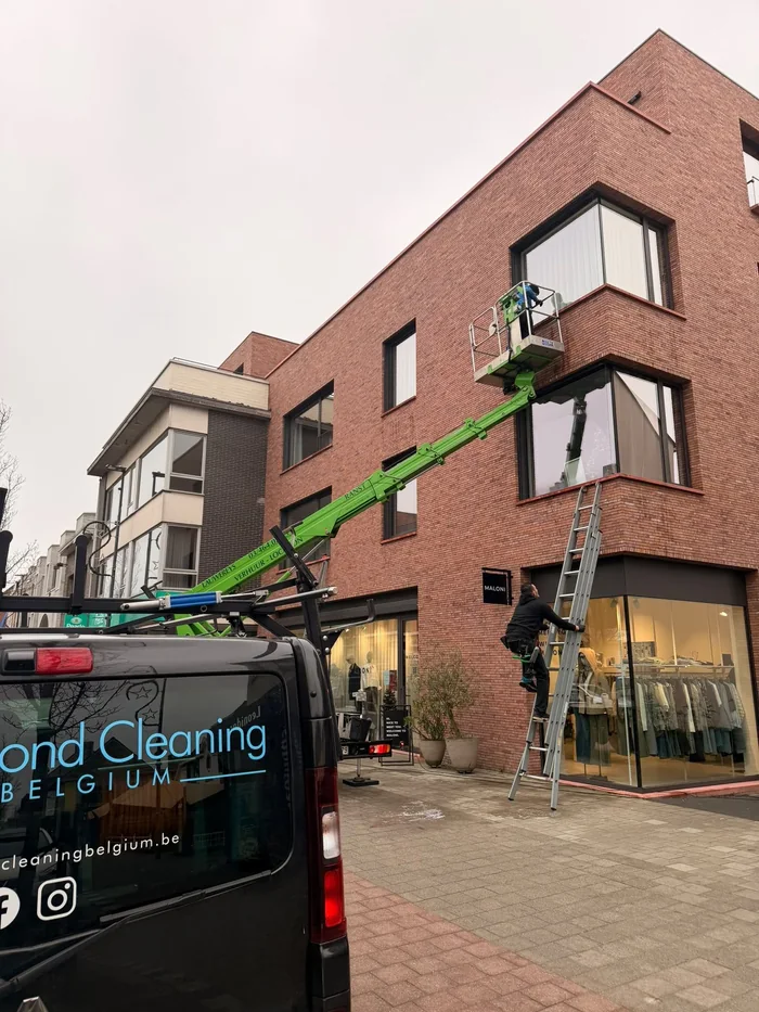 Hoogwerker en bestelwagen van Diamond Cleaning bij het reinigen van ramen