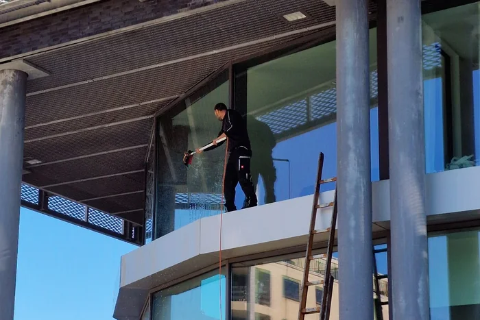 Medewerker wast een glaspartij op hoogte met een telescoopborstel