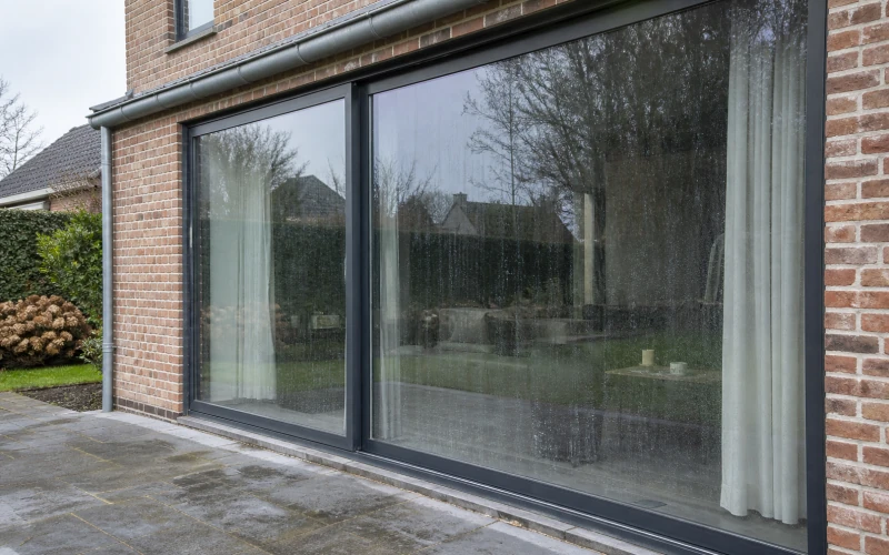 Glaspartij van een Vlaamse woning voor raamreiniging, met aanslag en regenstrepen