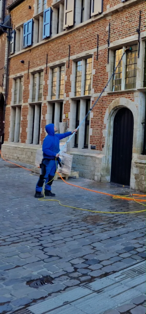 Medewerker reinigt een historische gevel van natuursteen en baksteen