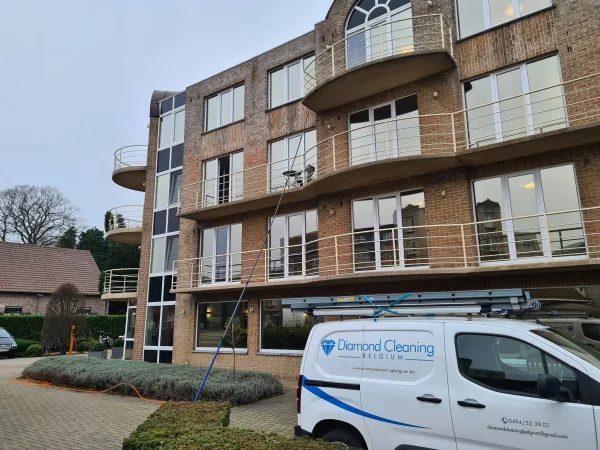 Bedrijfswagen van Diamond Cleaning voor een appartementsgebouw waar de ramen met een telescoopsteel gewassen worden